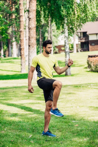 Handsome bearded man exercising on green lawn — Stock Photo