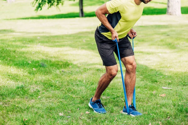 Ausgeschnittene Ansicht eines bärtigen Mannes, der mit Aufhängebändern im Park trainiert — Stockfoto