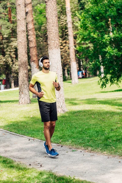 Bell'uomo barbuto che corre mentre ascolta musica in cuffia — Foto stock