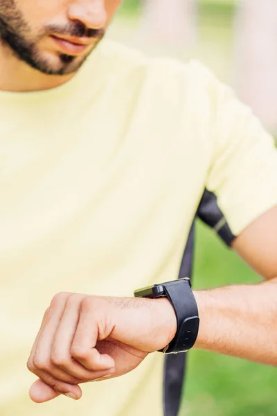 Cropped view of bearded man looking at fitness tracker outside — Stock Photo