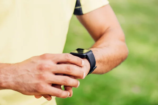 Ausgeschnittene Ansicht eines Mannes, der Fitnesstracker außerhalb berührt — Stockfoto