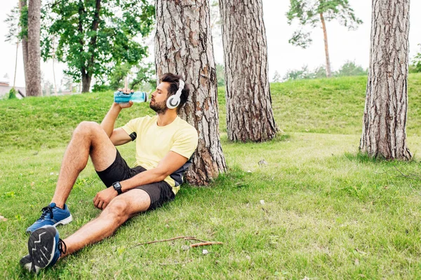 Handsome man with closed eyes drinking water near trees — Stock Photo