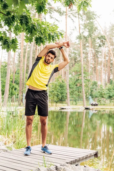 Beau sportif barbu s'exerçant près du lac dans la forêt — Photo de stock