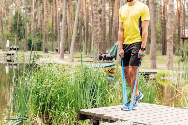Ausgeschnittene Ansicht eines Sportlers, der am See mit Federbeinen trainiert — Stockfoto
