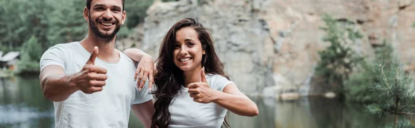 Tiro panorâmico de mulher alegre e homem feliz mostrando polegares para cima — Fotografia de Stock