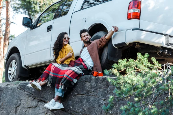 Hombre guapo tomando selfie con atractiva chica en gafas de sol cerca de coche - foto de stock