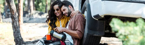 Colpo panoramico di donna che tiene la tazza mentre l'uomo versa il tè dal thermos — Foto stock