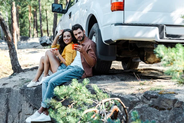 Selective focus of handsome man and attractive woman holding cups — Stock Photo