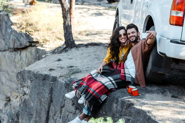 Fröhlicher Mann macht Selfie mit fröhlicher junger Frau in der Nähe von Auto — Stockfoto