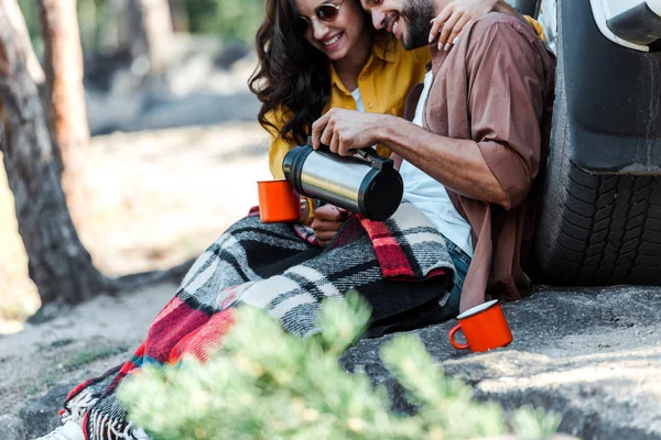 Abgeschnittene Ansicht von Mann, der Tee aus Thermoskanne in Tasse Frau gießt — Stockfoto