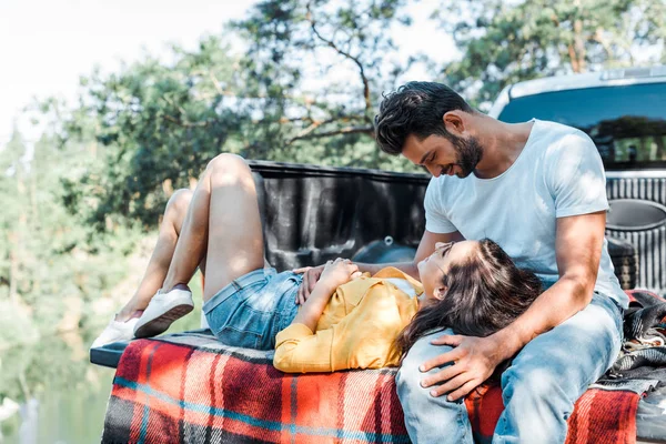 Красивий бородатий чоловік дивиться на щасливу дівчину, що лежить на плетеній ковдрі — стокове фото