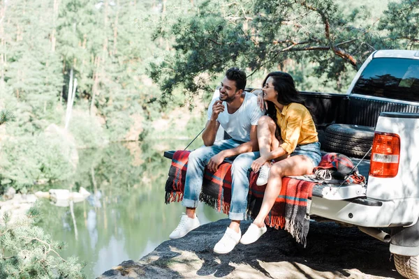 Cheerful bearded man sitting with attractive woman on plaid blanket — Stock Photo