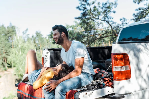 Felice uomo barbuto sorridente vicino alla donna sdraiato sulla coperta a quadri — Foto stock