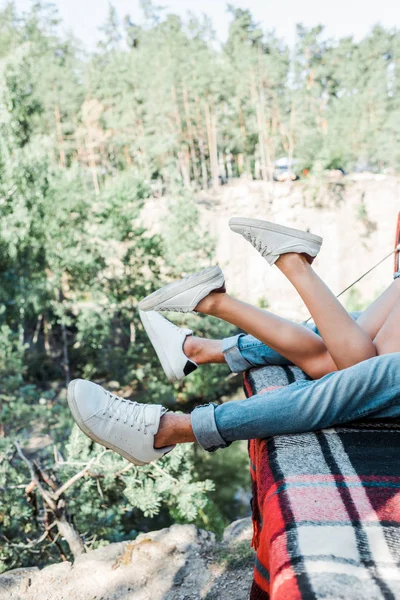 Cropped view of man and woman lying on plaid blanket in woods — Stock Photo