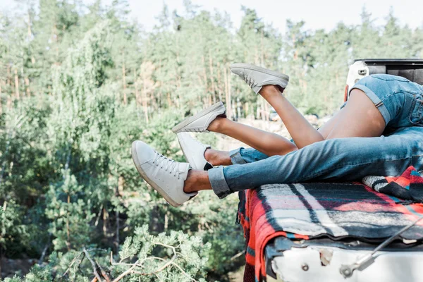 Vista recortada del hombre y la mujer acostados en una manta a cuadros en el bosque - foto de stock