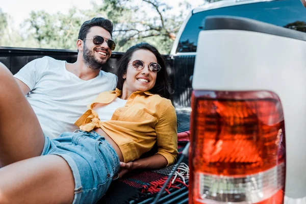 Selective focus of handsome man lying with happy woman on blanket in summertime — Stock Photo