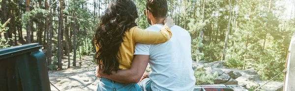 Panoramic shot of man and woman hugging while sitting in woods — Stock Photo