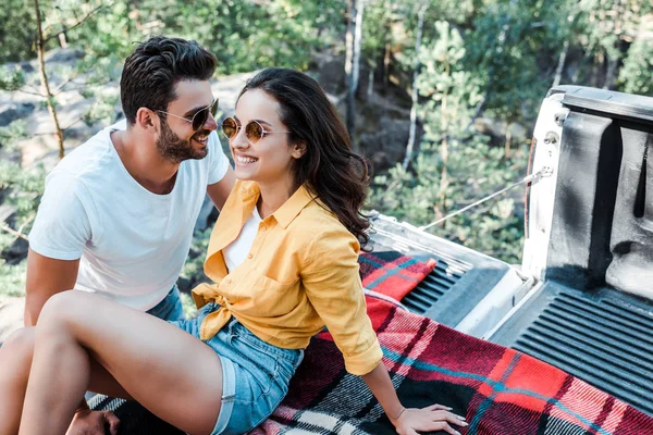 Happy bearded man smiling with young woman sitting on blanket in summertime — Stock Photo