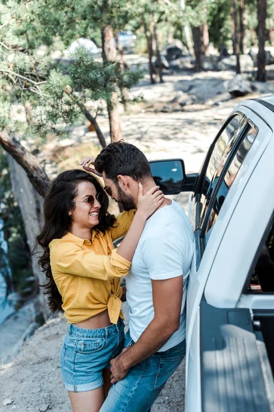 Attraente ragazza in occhiali da sole abbracciare bello uomo vicino auto — Foto stock