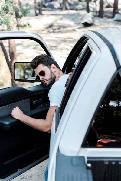 Избирательный фокус человека в солнцезащитных очках, открывающих дверь автомобиля — стоковое фото