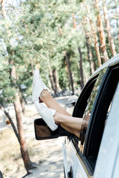 Cropped view of woman in white sneakers in woods — Stock Photo