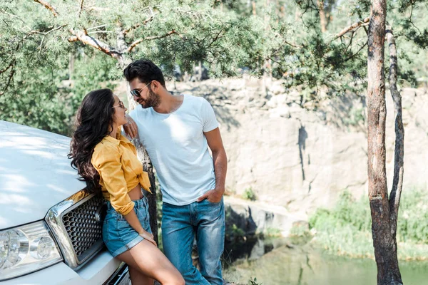 Uomo barbuto in occhiali da sole in piedi con la mano in tasca e guardando la ragazza — Foto stock