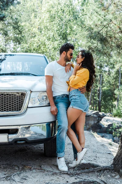 Bell'uomo che abbraccia donna sexy vicino auto nei boschi — Foto stock