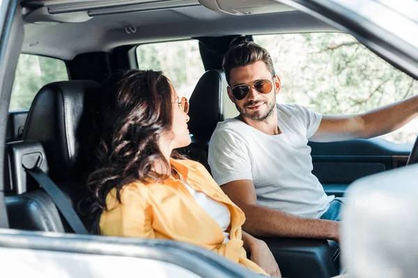 Foco seletivo de homem bonito olhando para a menina no carro — Fotografia de Stock