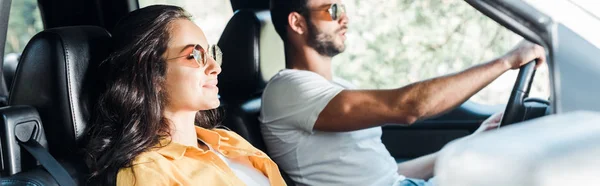 Panorámica tiro guapo hombre conducir coche cerca de chica — Stock Photo