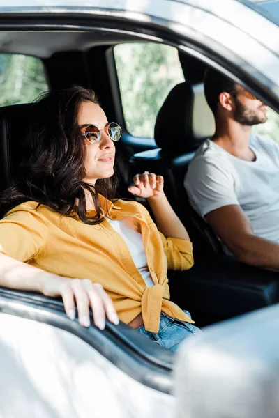 Селективный фокус привлекательной девушки рядом с водителем в автомобиле — стоковое фото