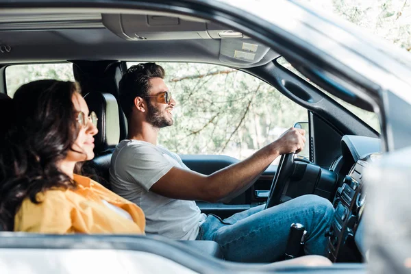 Selective focus of handsome man driving car near girl — Stock Photo