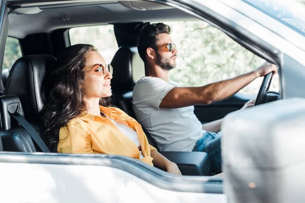 Selective focus of attractive girl near man driving car — Stock Photo