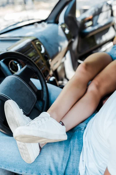 Ausgeschnittene Ansicht einer jungen Frau, die Mann im Auto Beine macht — Stockfoto