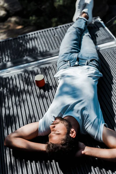 Overhead view of bearded man lying with closed eyes near cup — Stock Photo