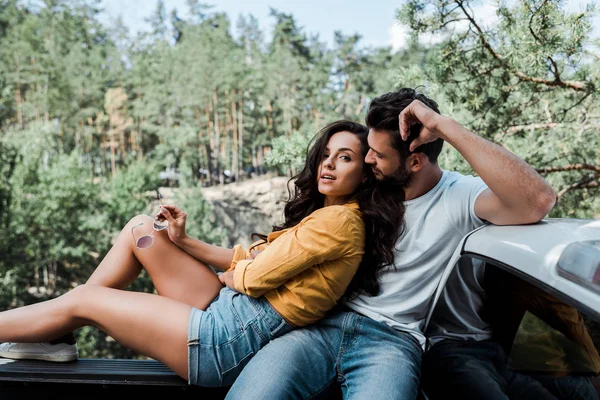 Barbudo hombre sentado y mirando a la chica en el bosque - foto de stock