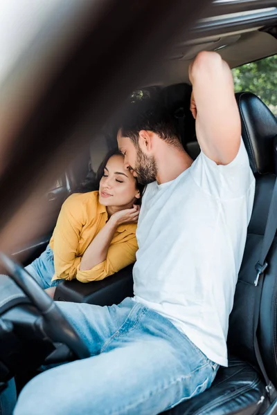 Messa a fuoco selettiva di giovane donna seduta vicino barbuto uomo in auto — Foto stock