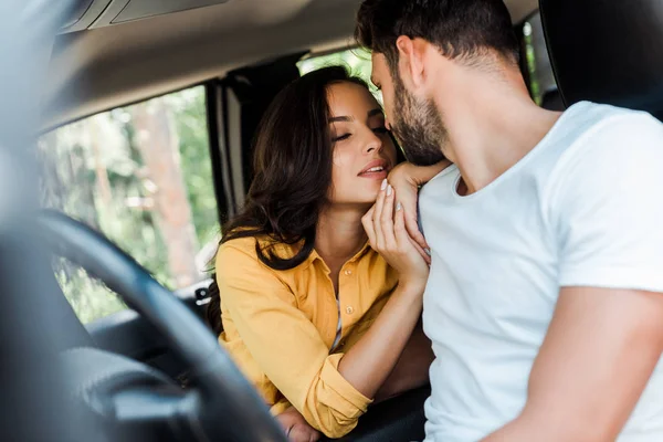 Selective focus of young woman with closed eyes sitting near bearded man in car — Stock Photo
