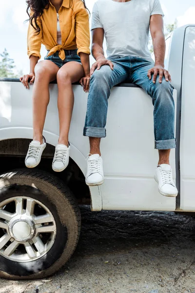 Cropped view of young man and woman sitting on car — Stock Photo