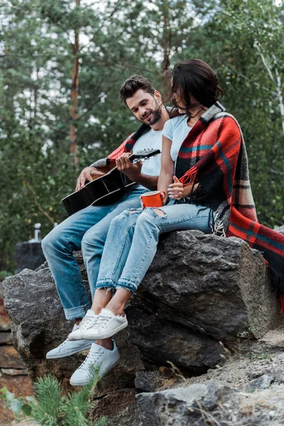 Мужчина играет на акустической гитаре рядом с девушкой — стоковое фото