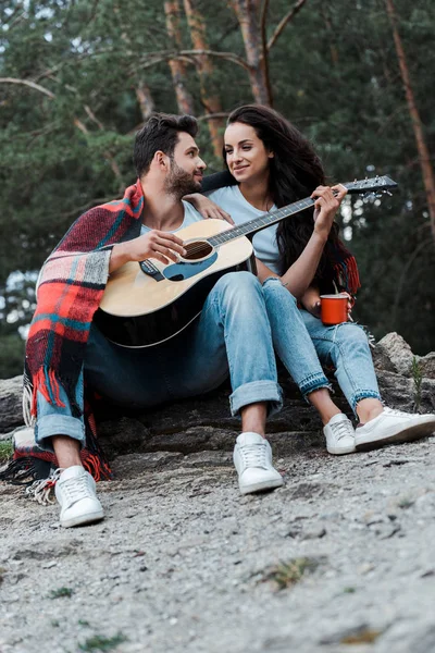 Enfoque selectivo de hombre feliz tocando la guitarra acústica cerca de chica - foto de stock