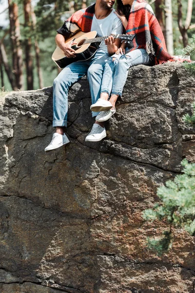 Обрізаний вид чоловіка, що грає на акустичній гітарі біля жінки в лісі — стокове фото