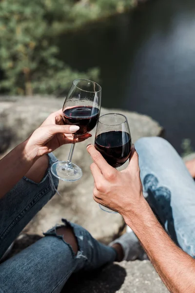 Vista recortada de hombre y mujer tintineo copas de vino - foto de stock