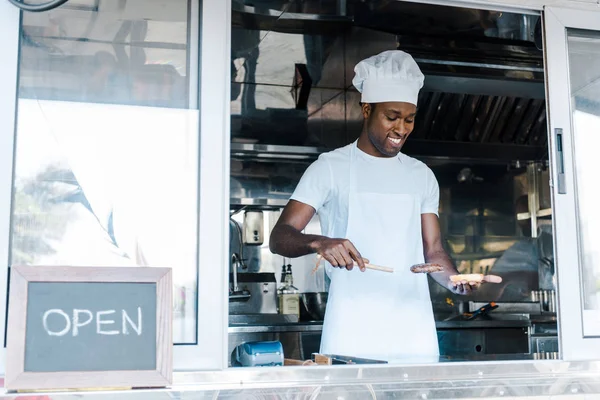 Felice uomo afriano americano in possesso di spatola durante la preparazione di hamburger — Foto stock