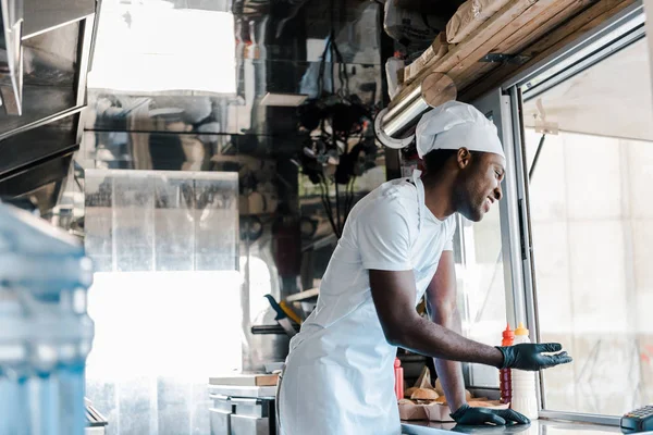Messa a fuoco selettiva di allegro chef afroamericano sorridente nel camion cibo — Foto stock