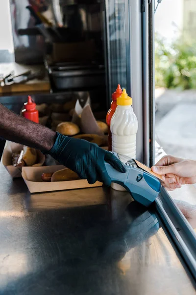 Обрізаний вид молодого чоловіка, який платить кредитною карткою біля афроамериканського шеф-кухаря — стокове фото