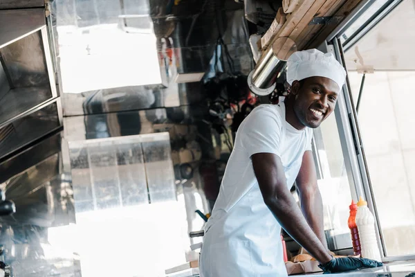 Вибірковий фокус щасливого афроамериканського шеф-кухаря, посміхаючись у харчовій вантажівці — стокове фото