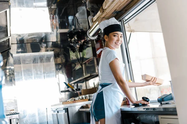 Heureux asiatique femme tenant carton plaque dans food truck — Photo de stock