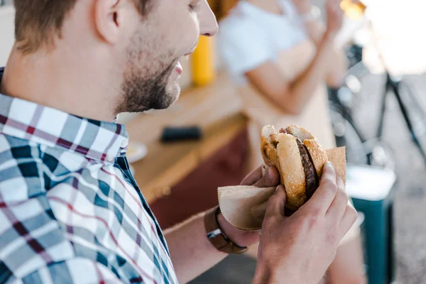 Visão cortada de homem alegre segurando hambúrguer saboroso — Fotografia de Stock