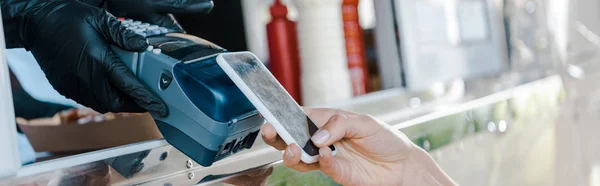 Panoramic shot of woman paying with smartphone near girl in food truck — Stock Photo