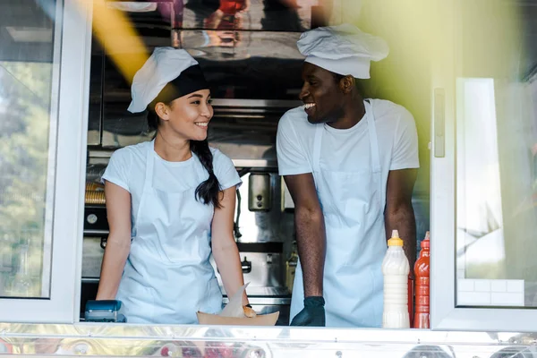 Selective focus of asian girl looking at african american man in food truck — Stock Photo